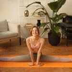 smiling fitness female doing stretching gymnastic split at home